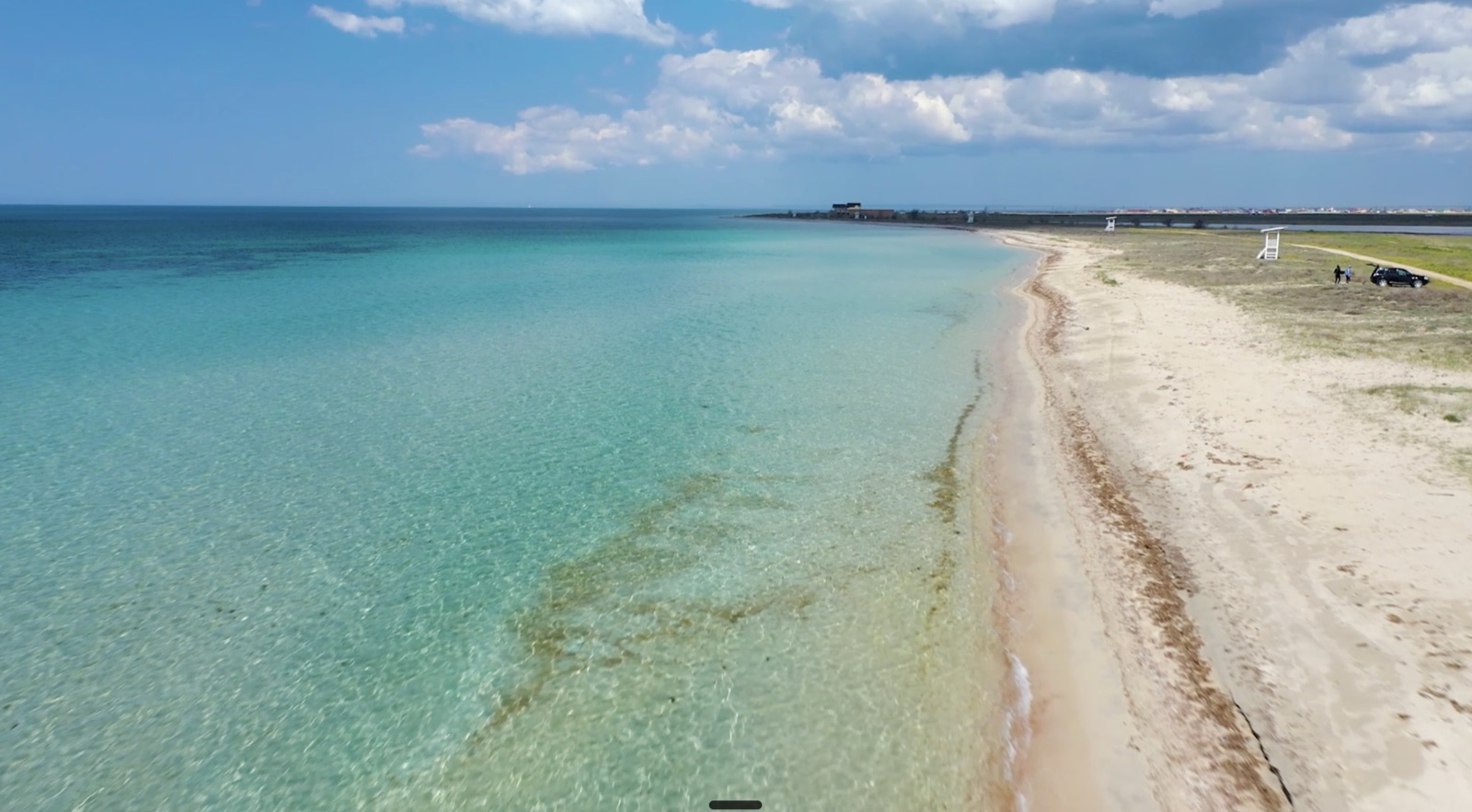 Широкий песчаный пляж западного побережья Крыма с бирюзовой мелкой водой
